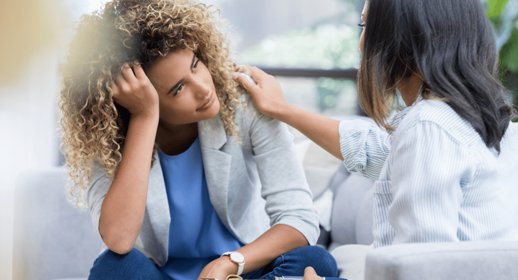 a woman in a blue shirt and jeans sitting on a couch