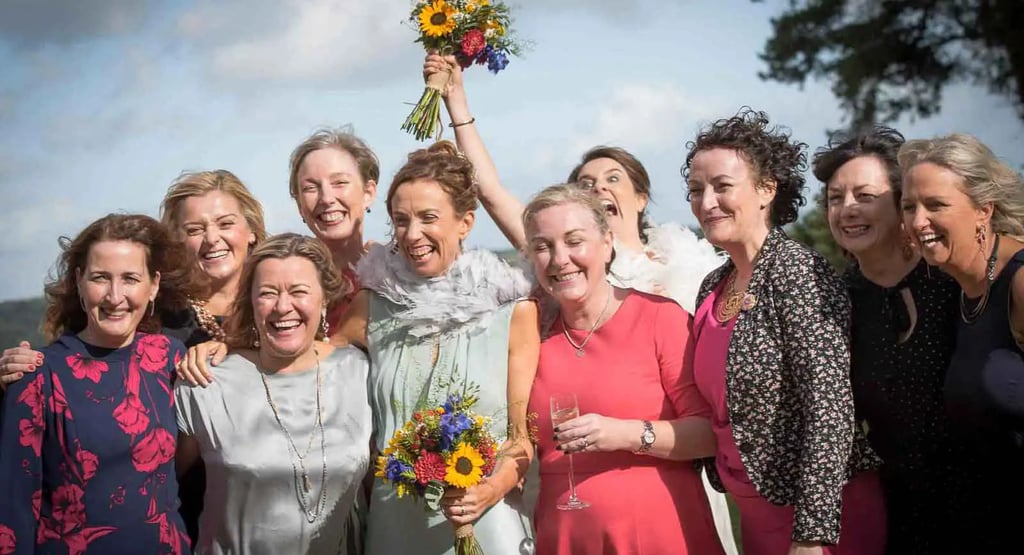 Smiling brides and bridesmaids celebrating a summer wedding with vibrant sunflower bouquets.