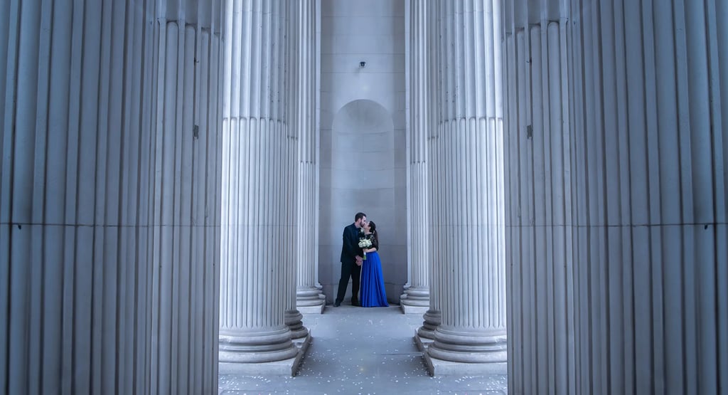 a man and woman standing in a room with columns