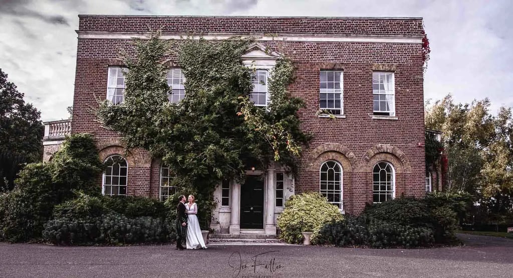 a bride and groom standing in front of a large brick building