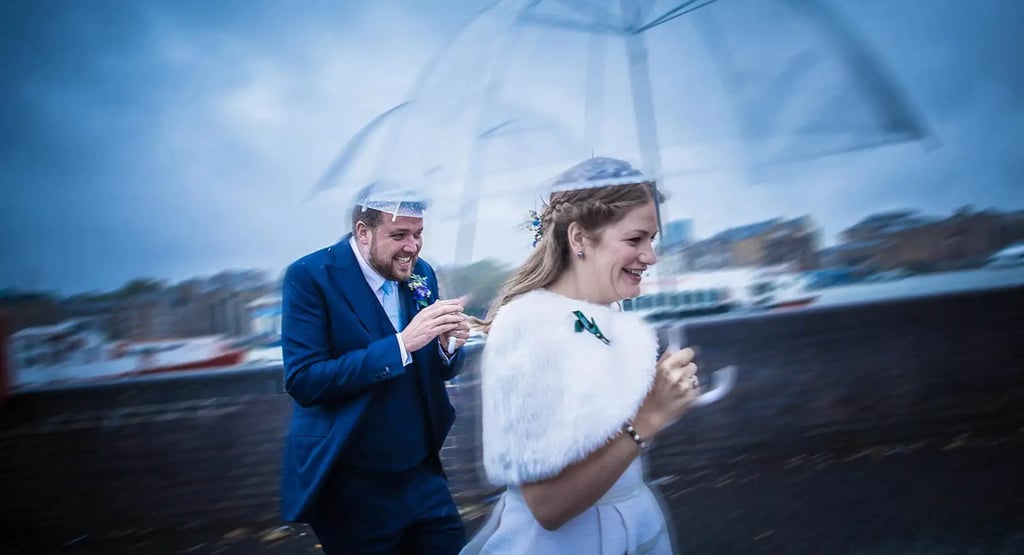 wedding couple with umbrellas running from the rain