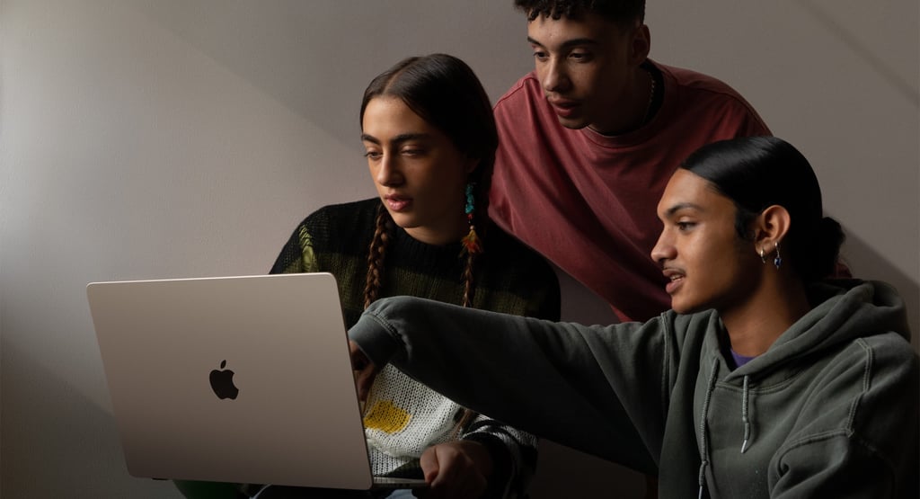three people sitting around a laptop computer
