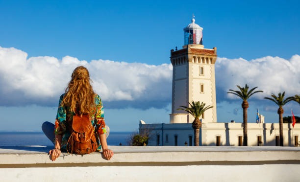 morocco tangier a woman sitting on a ledge looking at a lighthouse