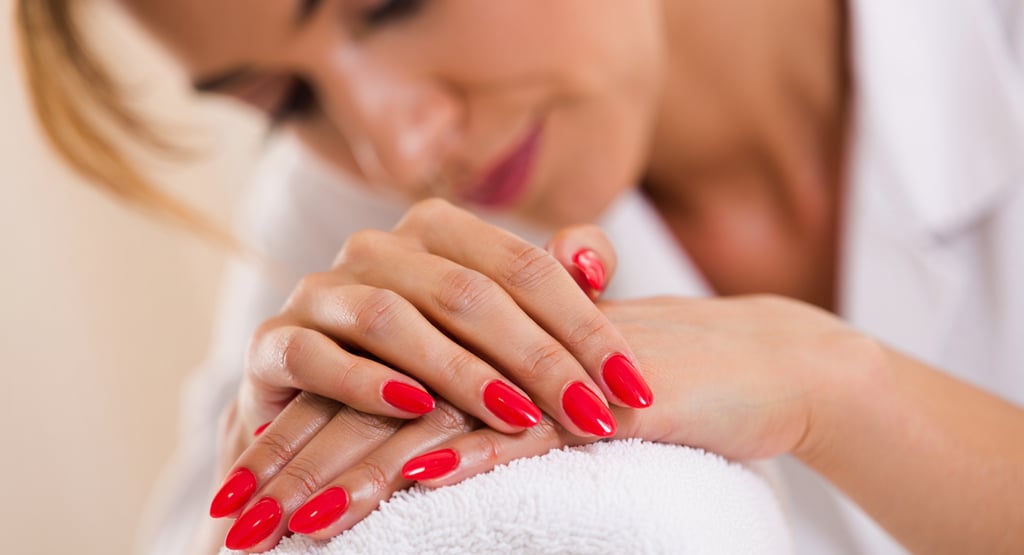 cliente emozionata della sua nuova manicure colore rosso con espressione rilassata in accappatoio 