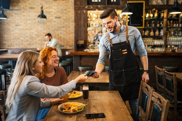 Dos mujeres pagando con tarjeta en un restaurante