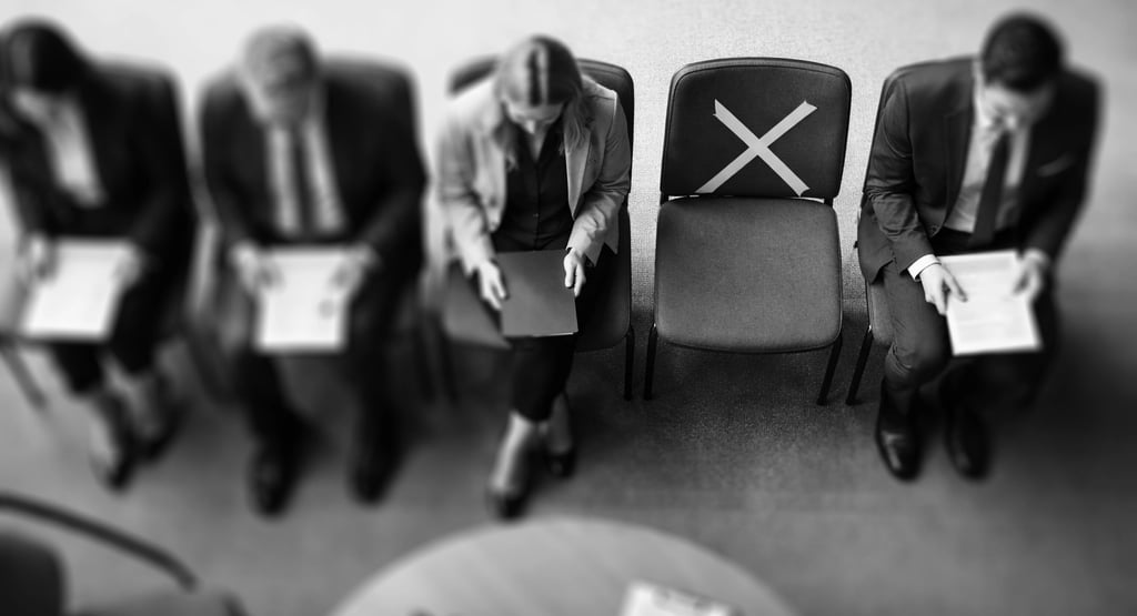top-down view of a row of chairs with job aplicants, with one empty chair