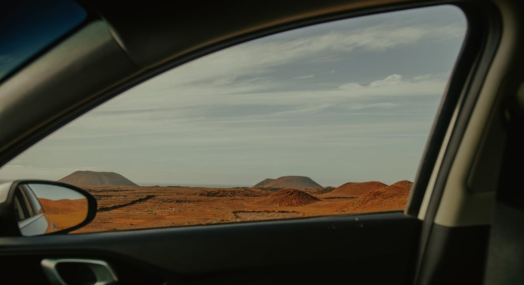 a car window with a view of a desert and volcanoes