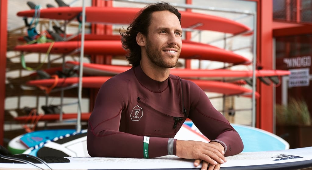 a man in a wetsuit is holding a surfboard