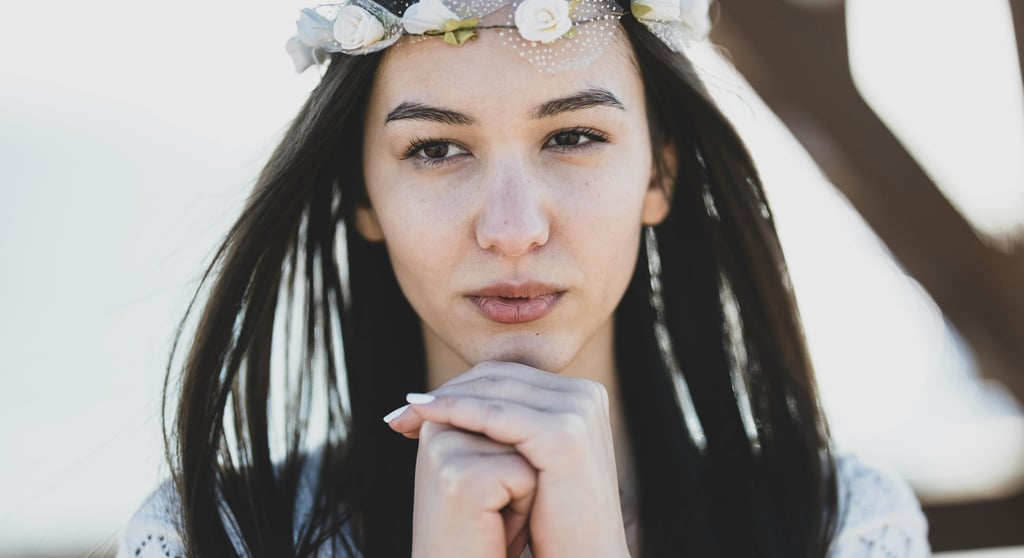 Portrait of a young woman wearing a white flower crown and lace dress for a boho style wedding photoshoot.