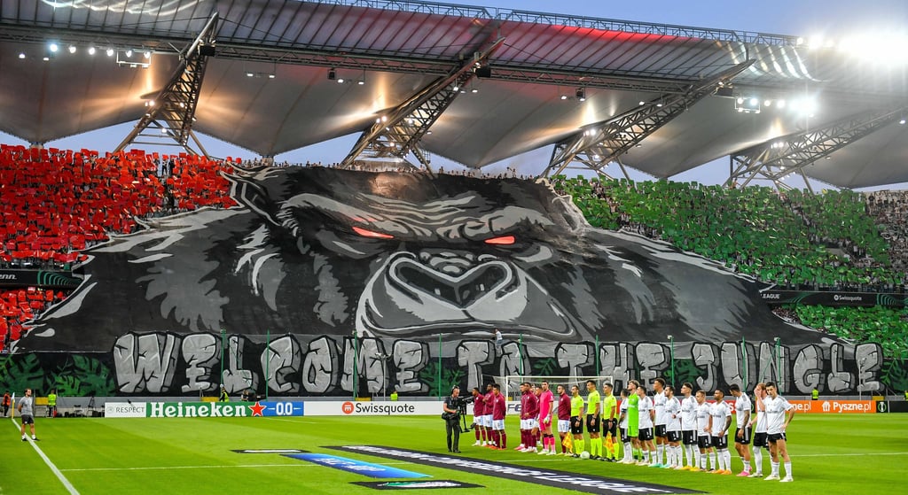 Ultras von Legia Warschau im Stadion mit Fahnen, Bannern und Choreografie
