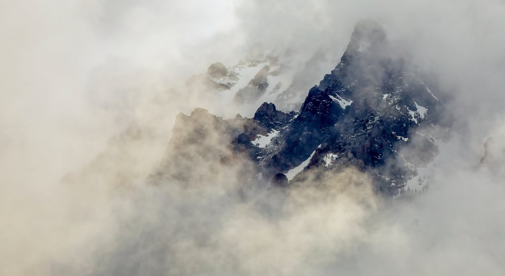 A minimalist photo of a mountain ridge surrounded by fog during golden hour.