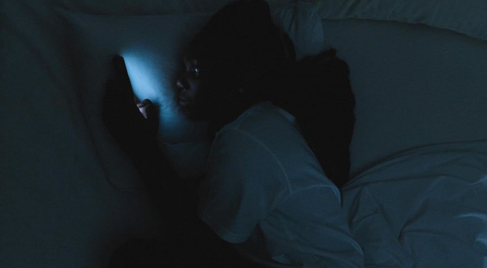 a person laying in bed with a cell phone