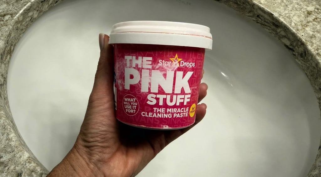 Hand holding The Pink Stuff Miracle All Purpose Cleaning Paste over a bathroom sink
