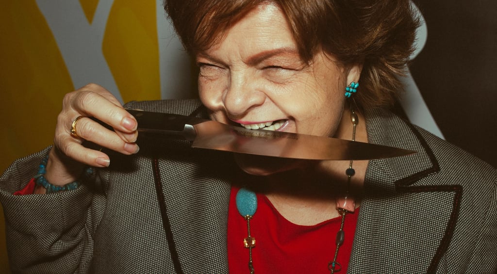 Mujer mayor divertida mordiendo un cuchillo y riendo para la marca de cuchillos Zwilling