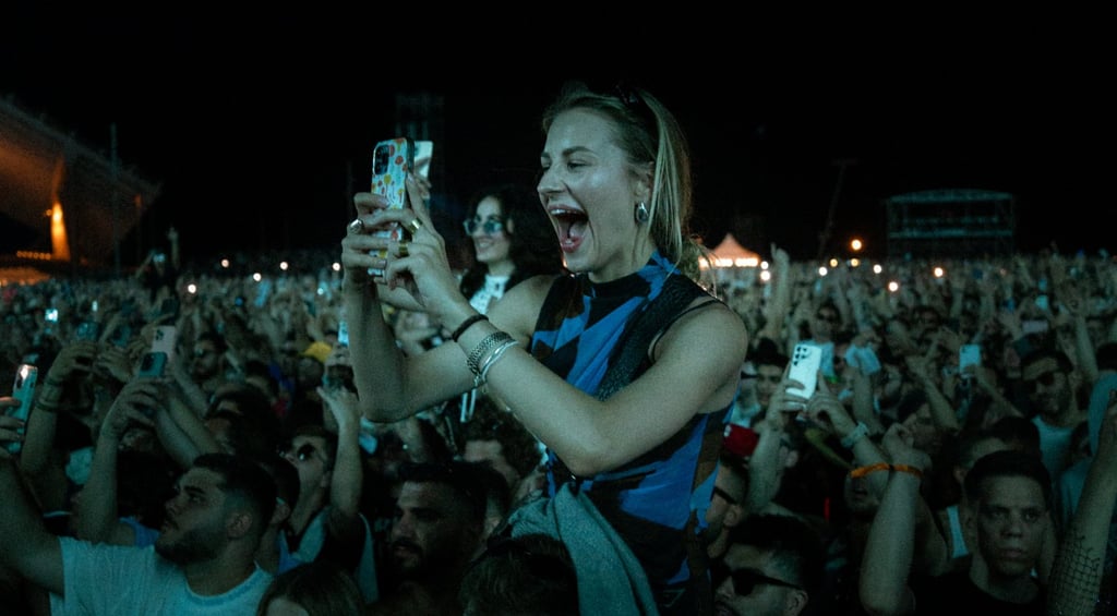 Excited woman on someone's shoulders, filming a concert. Energetic crowd with phones raised in the dark. Live music atmospher