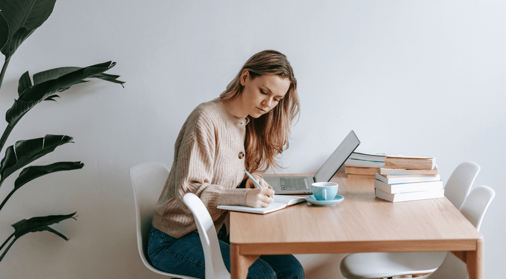 a woman sitting at a table with a laptop and a laptop