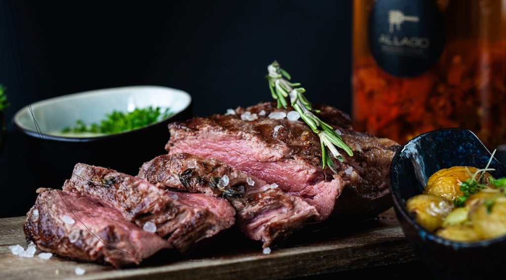 Geschnittenes medium-rare Ribeye-Steak mit Meersalz und Rosmarin auf Holzbrett.