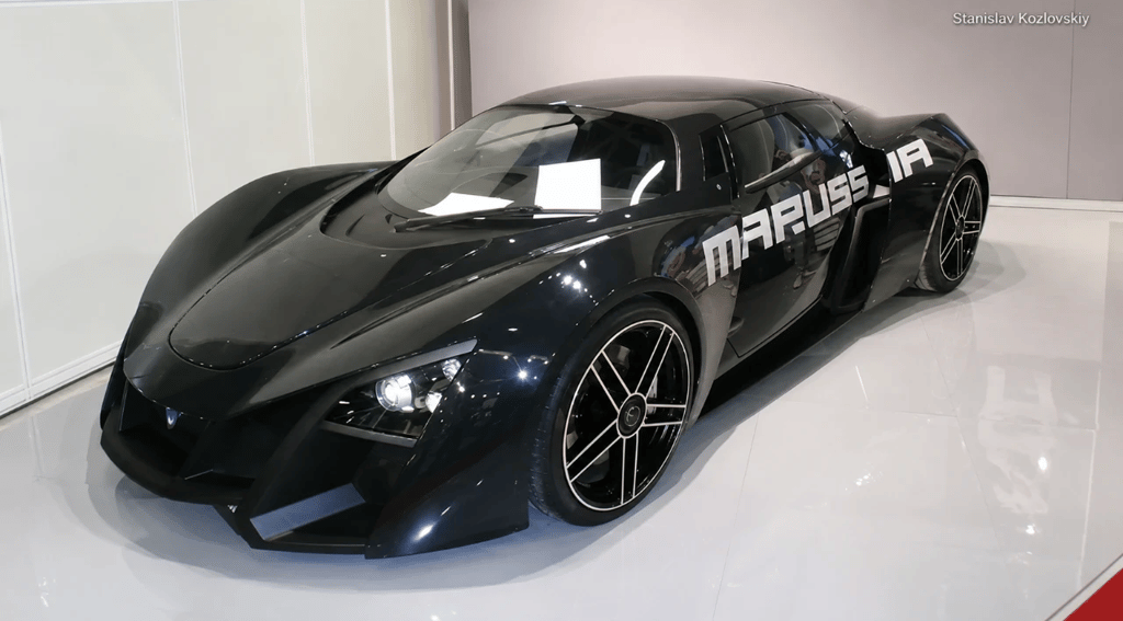 Marussia B2 preto em exposição com design futurista e visual de supercarro