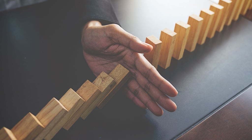 a person holding a wooden block with a hand and stopping them from falling