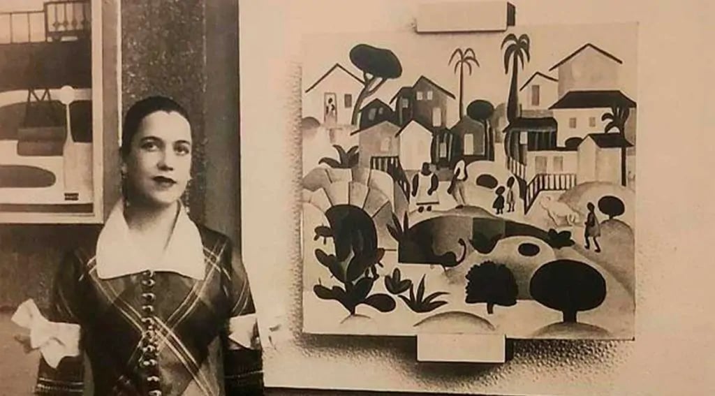foto de Tarsila do Amaral, ao lado de uma quadro pintado por ela.