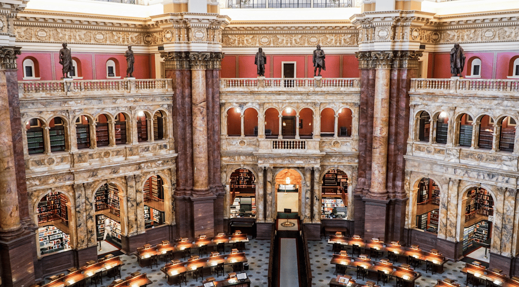 An ornate historic library interior with multiple levels of bookshelves and classical architecture