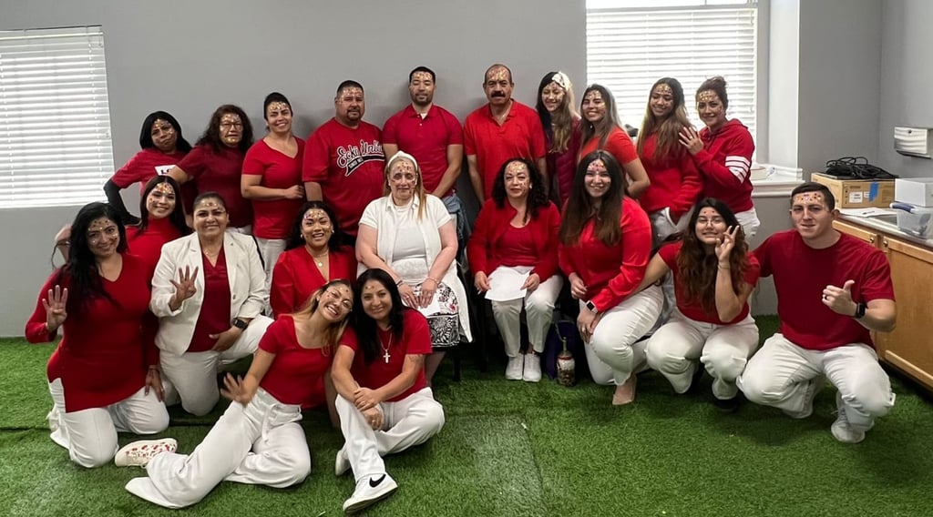 Diverse group of coworkers posing in red shirts and white pants for a workplace team building event.