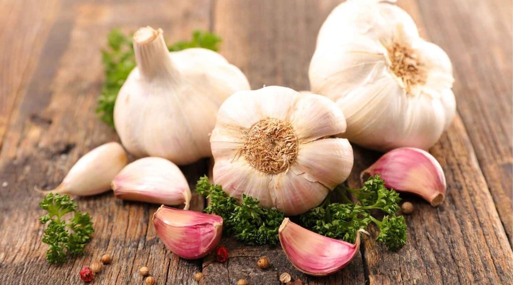 L'ail. Du bulbe à votre assiette. De la terre à votre cuisine.3 gousses d'ails sur une table en bois