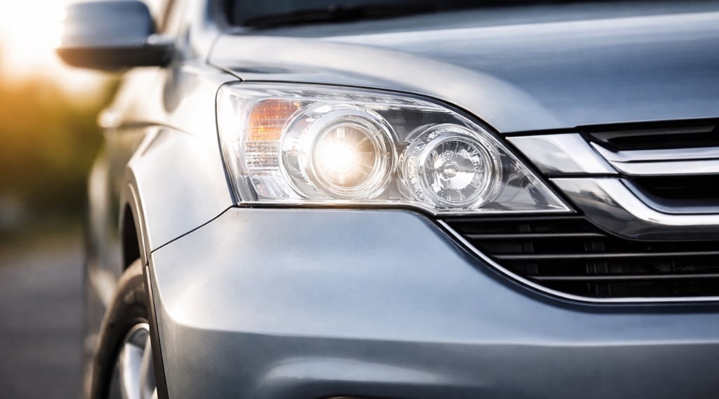 Detalhe frontal de SUV com farol aceso e design moderno em close, imagem parcial