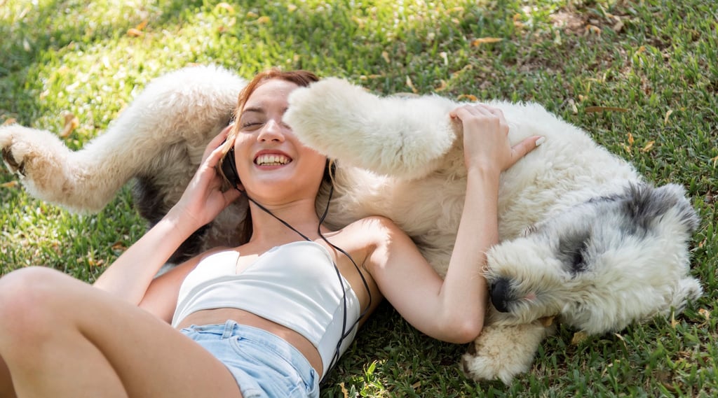 a woman laying on the grass with her dog