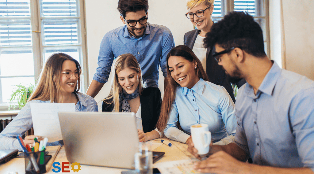 a group of people sitting around a laptop computer
