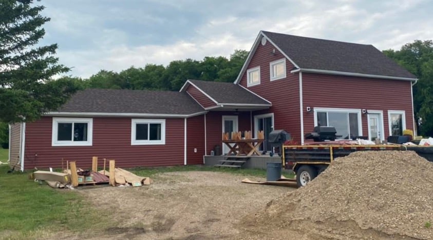 Red vinyl siding on a modern two-story country house with white window trim and a new shingle roof.