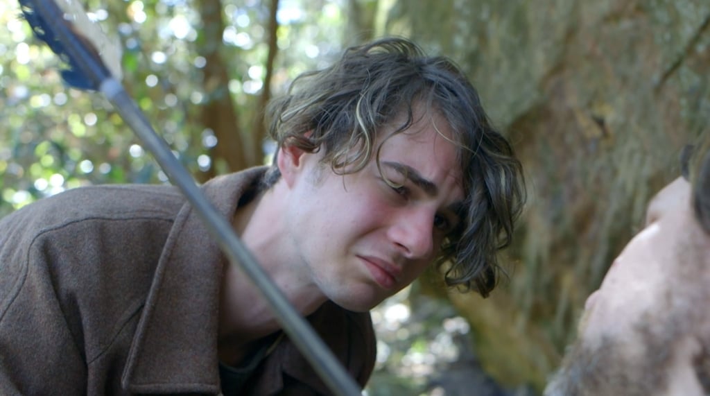 a man in a brown jacket is holding a sword