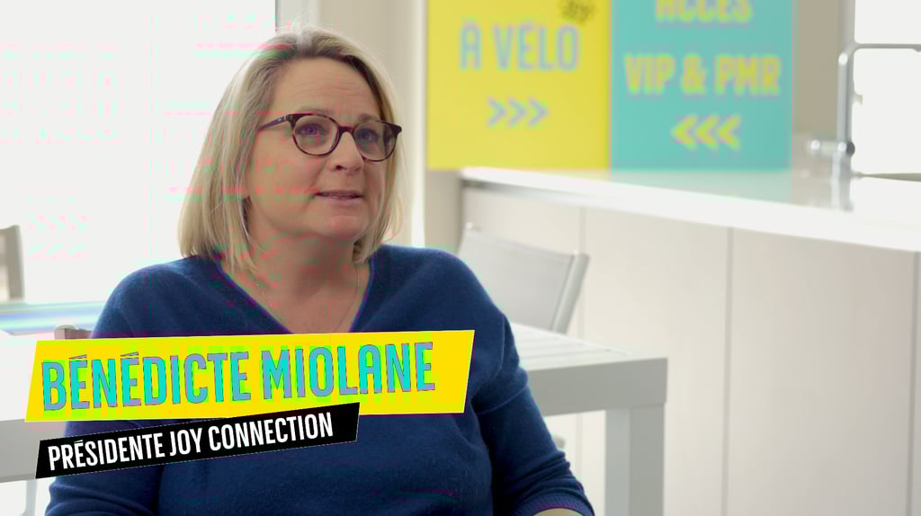 a woman in a blue sweater and glasses sitting at a desk