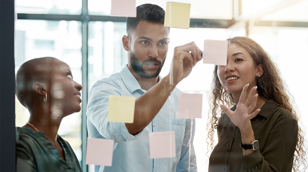 Diverse team brainstorming with sticky notes on glass wall during a strategy session
