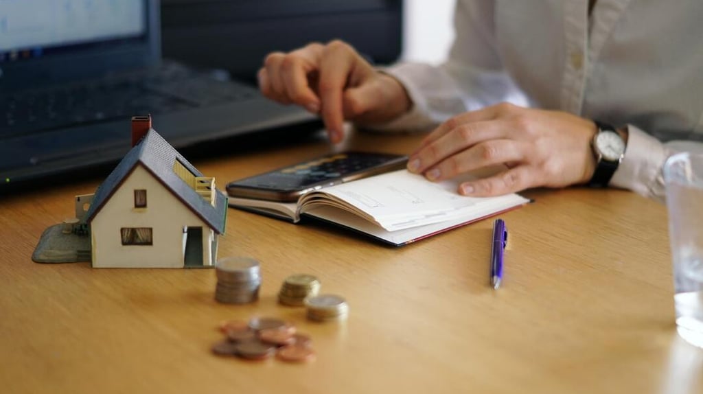 hombre hacienco las cuentas con dinero y una maqueta de una casa