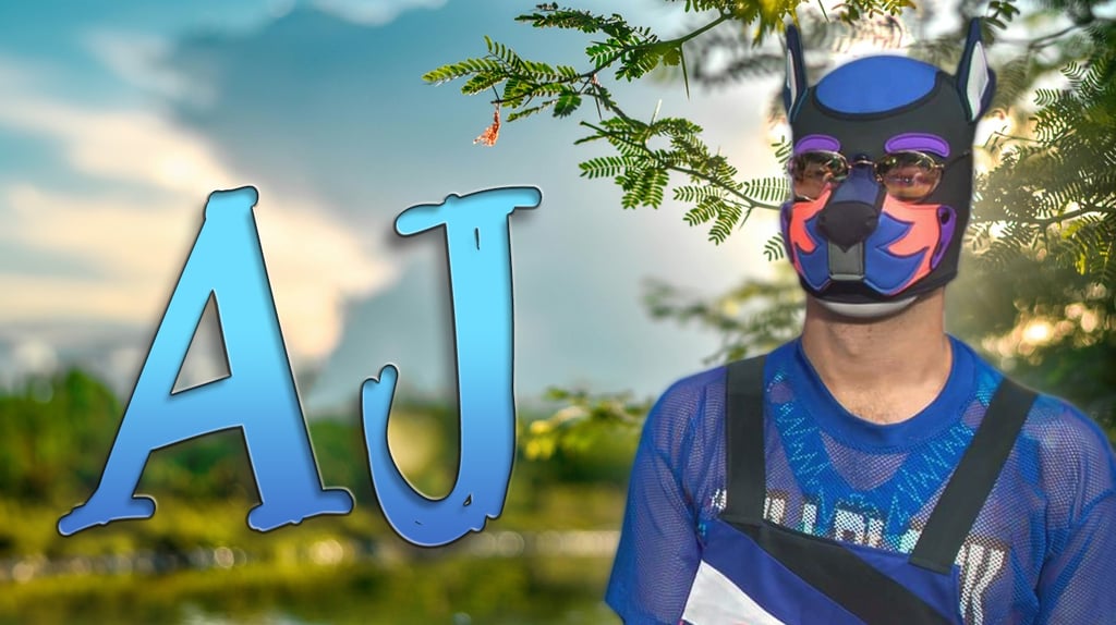 A man in a pup mask posing outdoors, with name plate: AJ