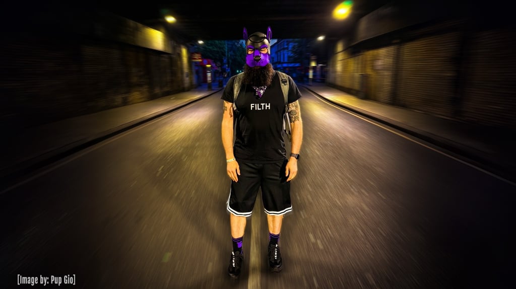 Man in pup mask standing in the middle of a deserted street at night.