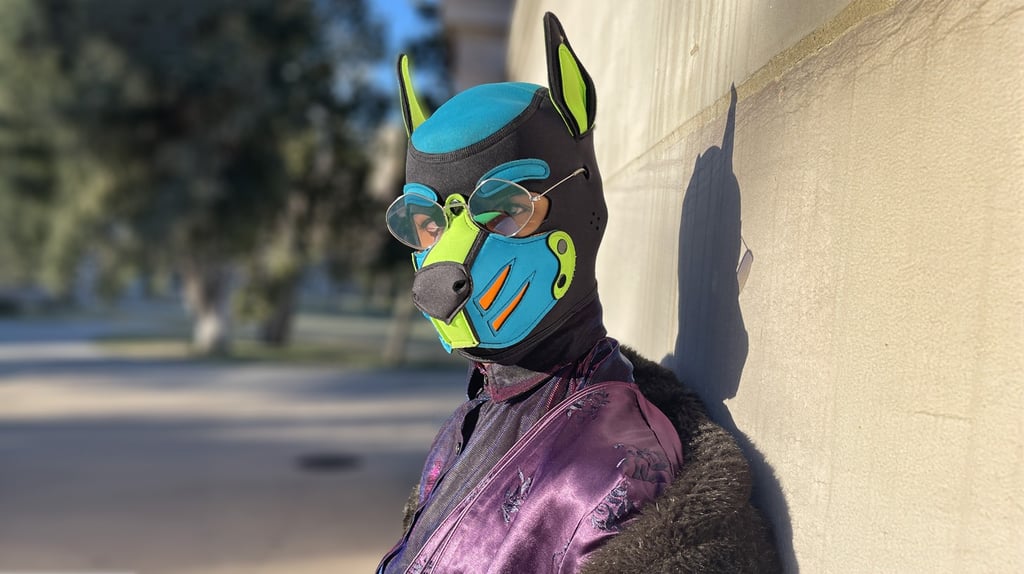 A man in a pup mask posing against a wall.