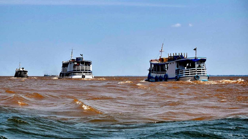 two boats are in the water near the shore