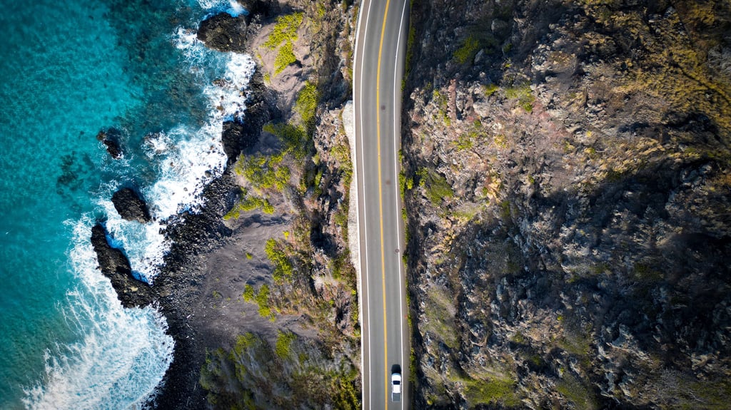 a car driving down a road next to a body of water