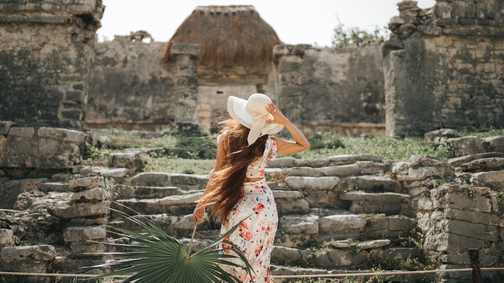 Back View o Woman in a Summer Outfit Looking at House of the Halach Uinic at Mayan Ruins in Tulum.