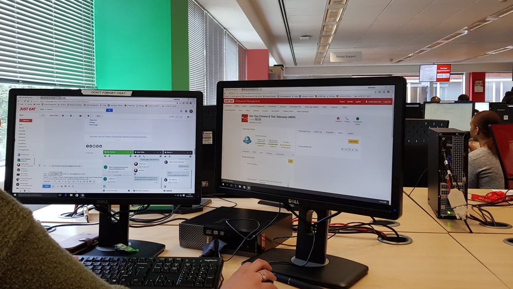a woman sitting at a desk with two monitors and a keyboard
