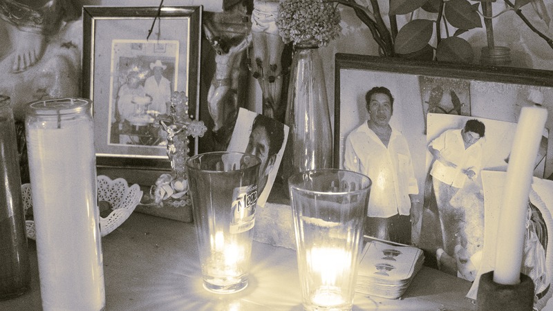 Altar mexicano del Día de los Muertos con fotos familiares antiguas, velas altas de oración