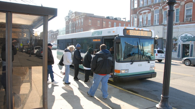 A group of people at a bus stop boarding a Jefferson City bus