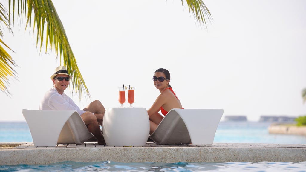 two people sitting on lounge chairs in front of a pool