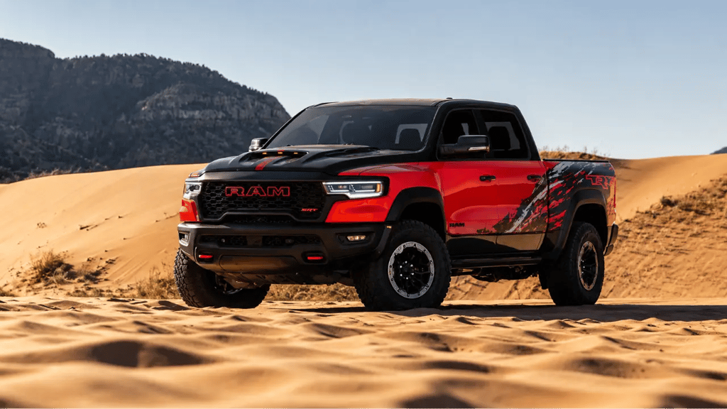 Picape Ram 1500 TRX vermelha estacionada em dunas no deserto com visual off-road agressivo e céu lim