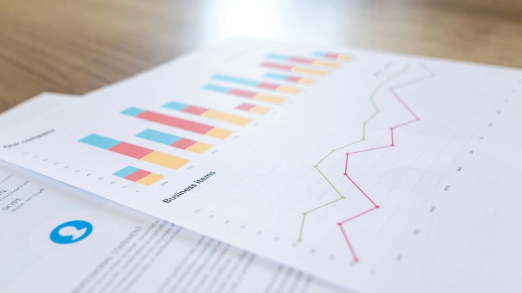 Two overlapping sheets of paper on a tabletop, the top one covered in graphs, a bar graph and a line graph.