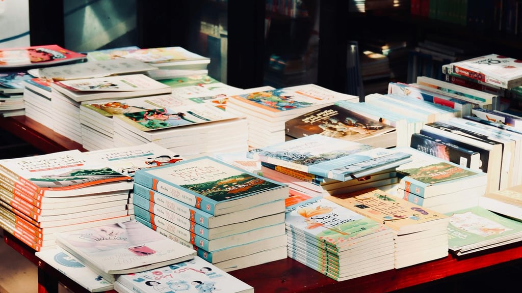 A selection of piles of books upon a table in what appears to be a bookshop.