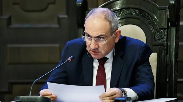 Armenian Prime Minister Nikol Pashinyan wearing a suit and glasses while speaking at a meeting.