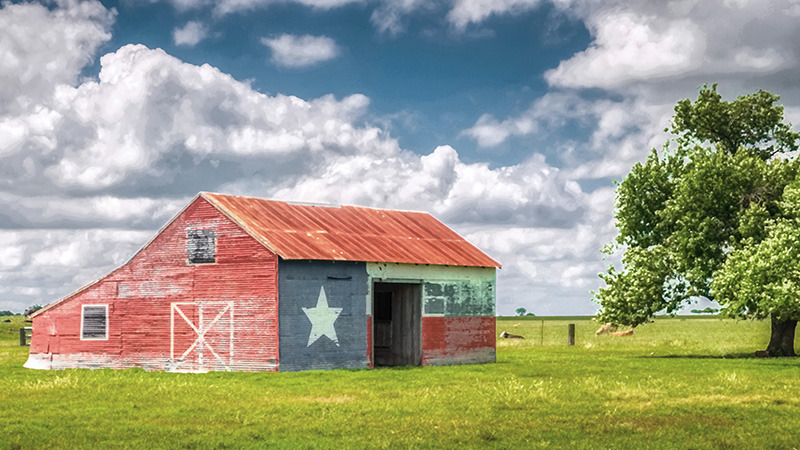 Rustic barn painted with Texas state flag motif, showcasing Texas pride in a rural Texas countryside setting